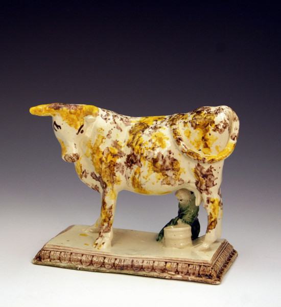 ANTIQUE ENGLISH POTTERY FIGURE OF A COW ON BASE