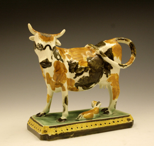 Prattware pottery figure of a cow and calf on base.