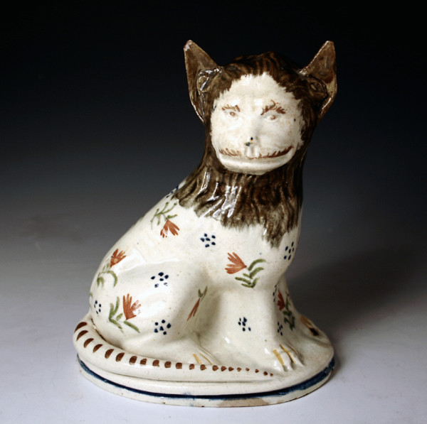 EARLY POTTERY FIGURE OF A SEATED LION IN PRATT COLOURS