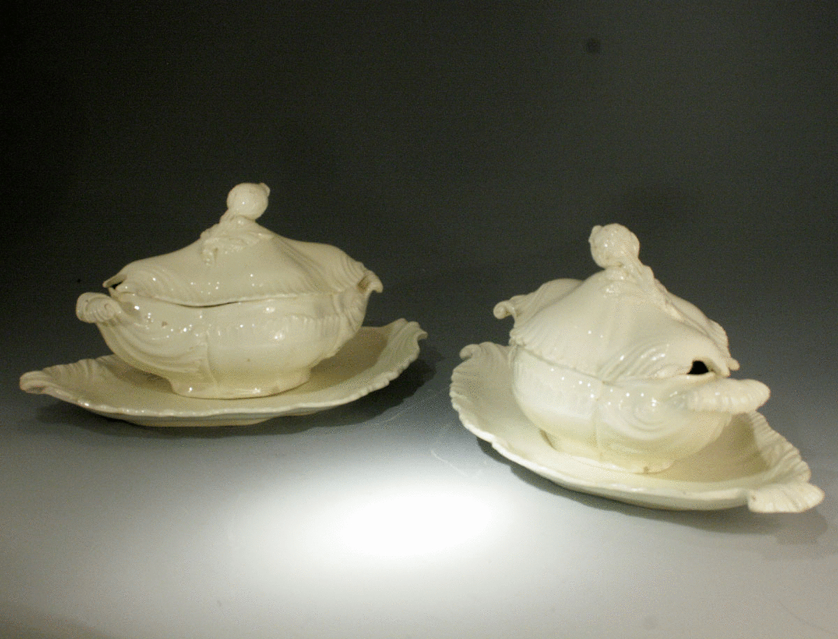 PAIR OF CREAMWARE POTTERY TUREENS WITH COVERS AND STANDS