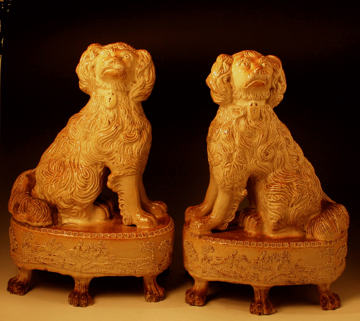 PAIR OF POTTERY FIGURES OF SPANIEL DOGS SEATED ON BASES