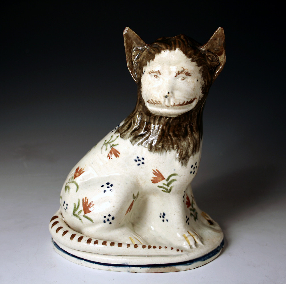 EARLY POTTERY FIGURE OF A SEATED LION IN PRATT COLOURS