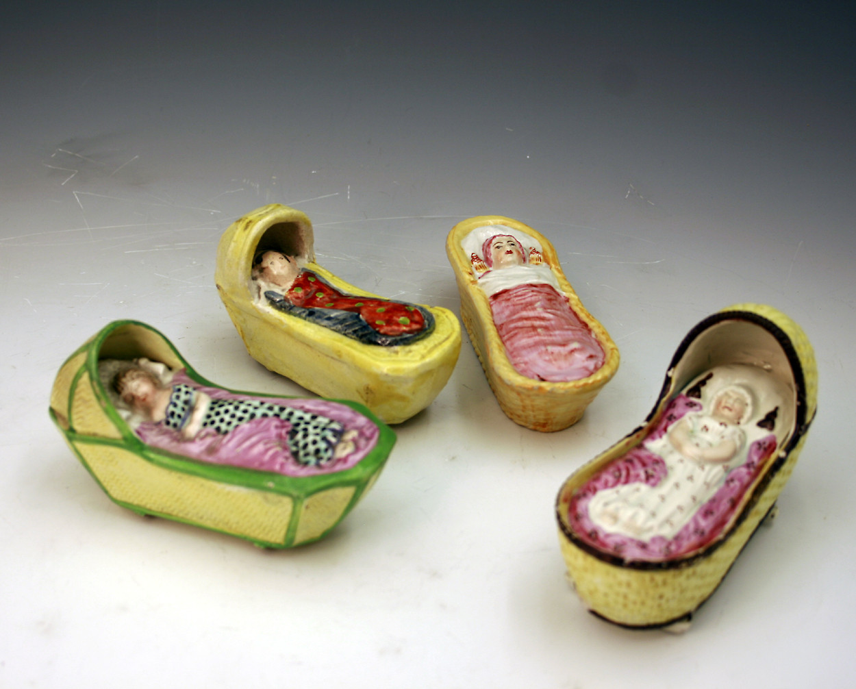 Collection of antique English pottery cradles with figure of a baby 
