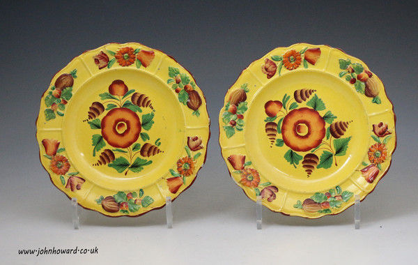 Pair of canary yellow pottery plates with bright enamel decoration early 19th century British