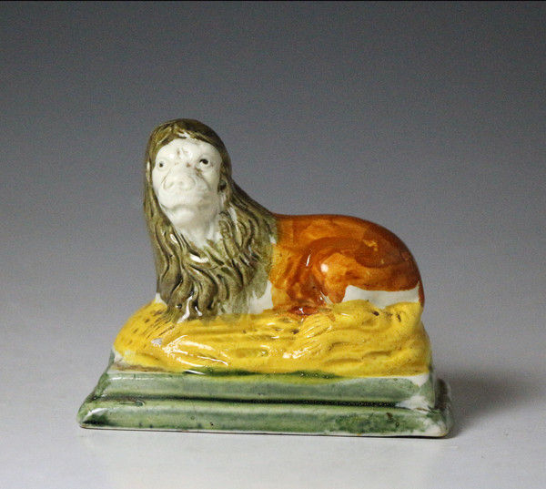 Antique English pottery figure of a lion on ochre and green base in Pratt colours , early 19th century