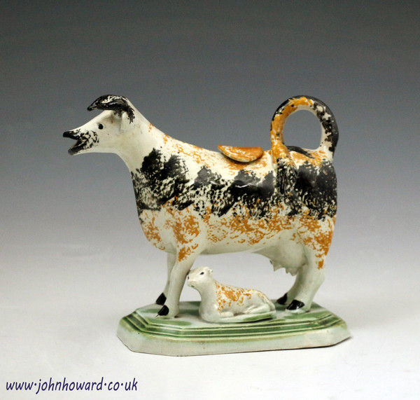 Antique English pottery cow creamer with calf on oblong base circa 1810