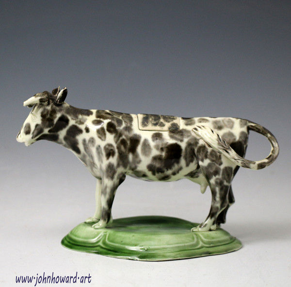 Antique pottery cow creamer figure on green base, a rare early example of small proportions.