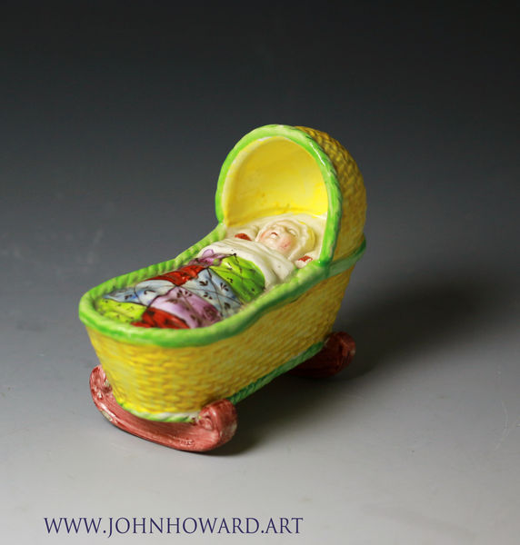 Staffordshire pottery baby asleep in a canary yellow ground cradle. Antique English period early 19th century