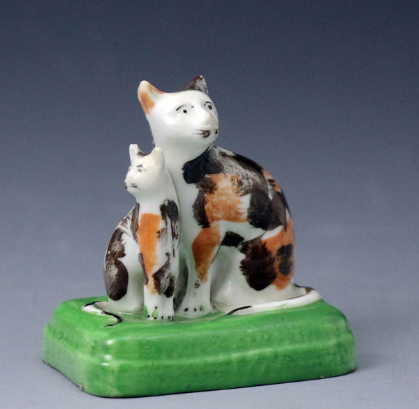 Staffordshire porcelain calico cat with kitten on green base, antique period early 19th century