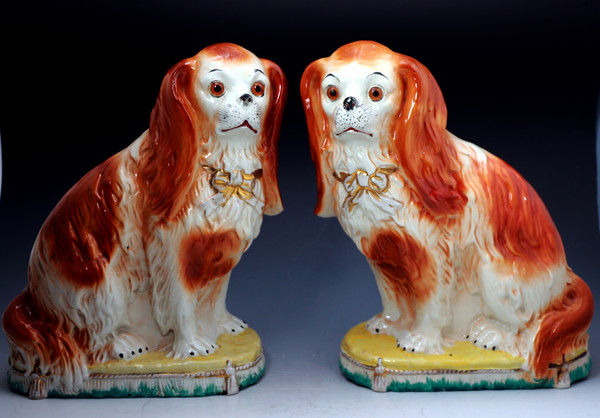 PAIR OF STAFFORDSHIRE POTTERY SPANIELS WITH GLASS EYES SITTING ON CUSHION BASES