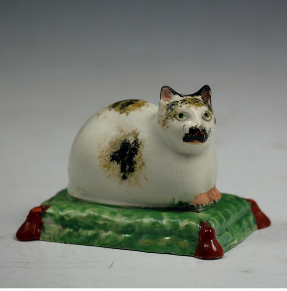 Staffordshire pearlware pottery figure of a reclining cat on a cushion c1820