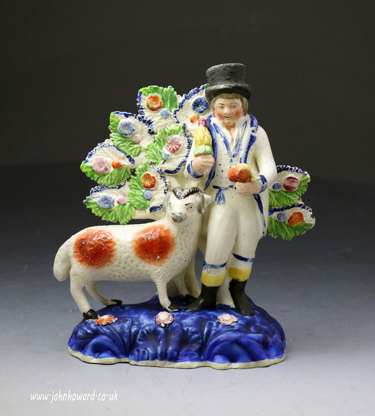 Antique Staffordshire pottery of a farmer standing by a ram modeled on a  distinctive blue base.