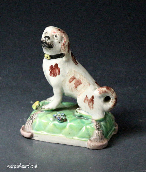 Staffordshire pearlware pottery figure of a seated dog on tassled cushion base early 19th century English.