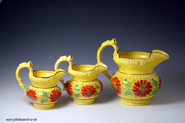 Set of three antique Staffordshire pottery canary yellow pitchers with bright enamel decoration circa 1825.