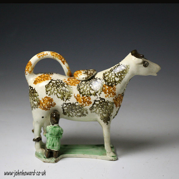 Antique pearlware pottery figure of a cow creamer with hobbled legs and milk maid. circa 1800