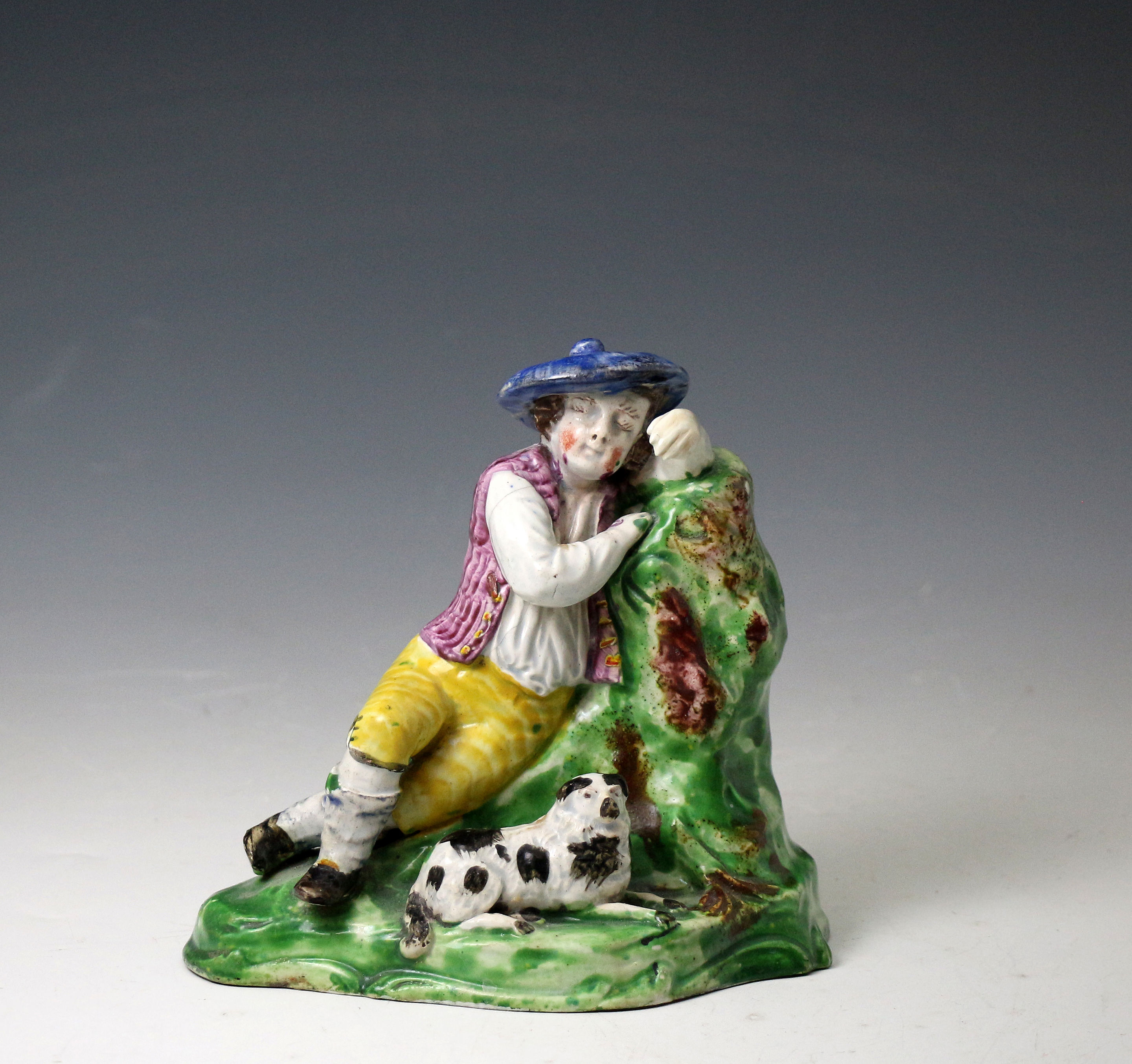 Antique Staffordshire pottery figure of a slumbering shepherd boy and his dog, early 19th century England.