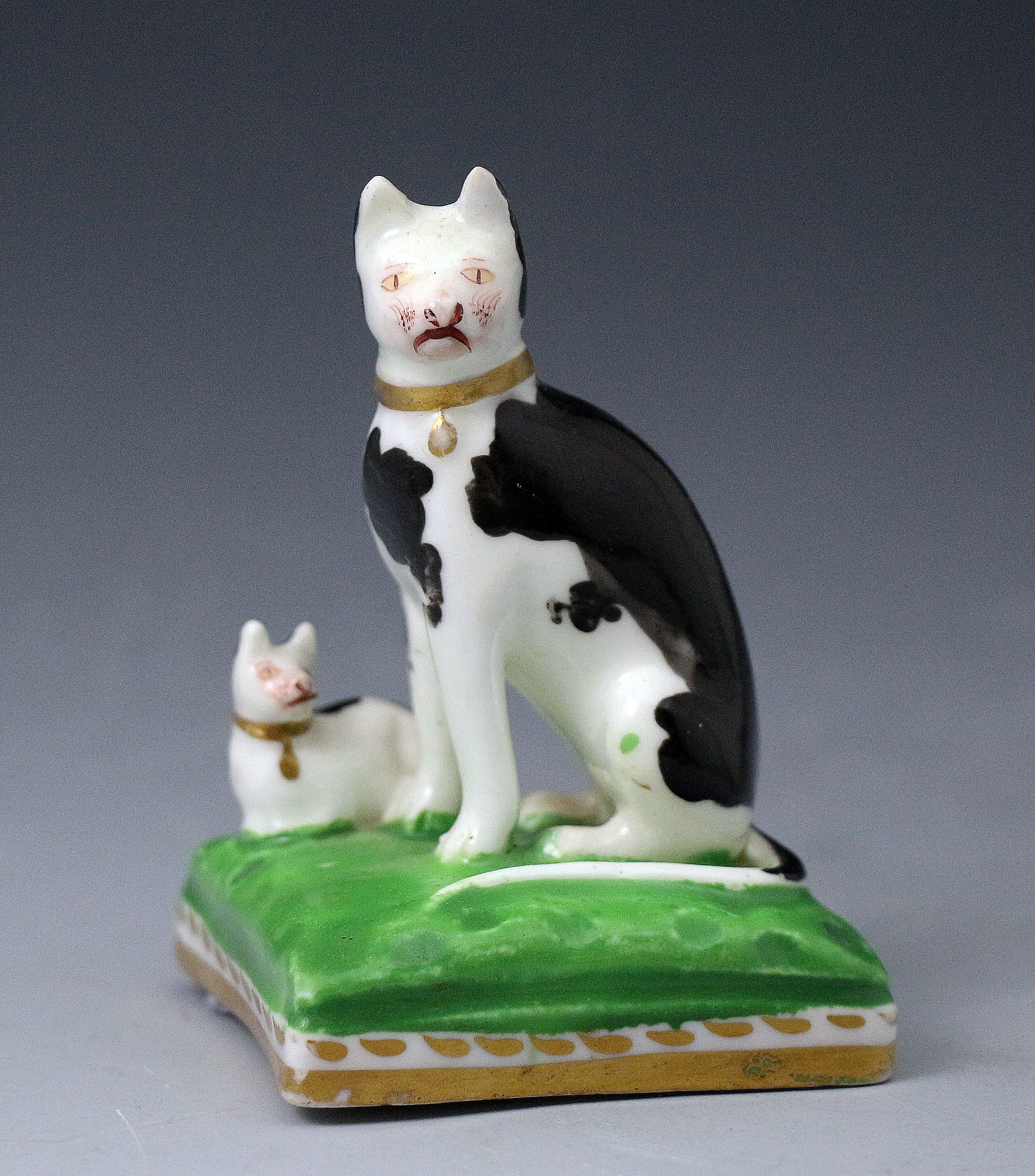 Staffordshire porcelain antique figure of a black and white cat with kitten on green and gilt cushion base.