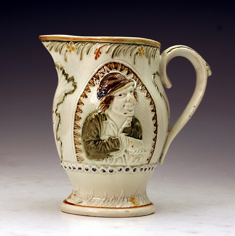 Prattware pottery pitcher with relief moulded decorative panel of the miser.