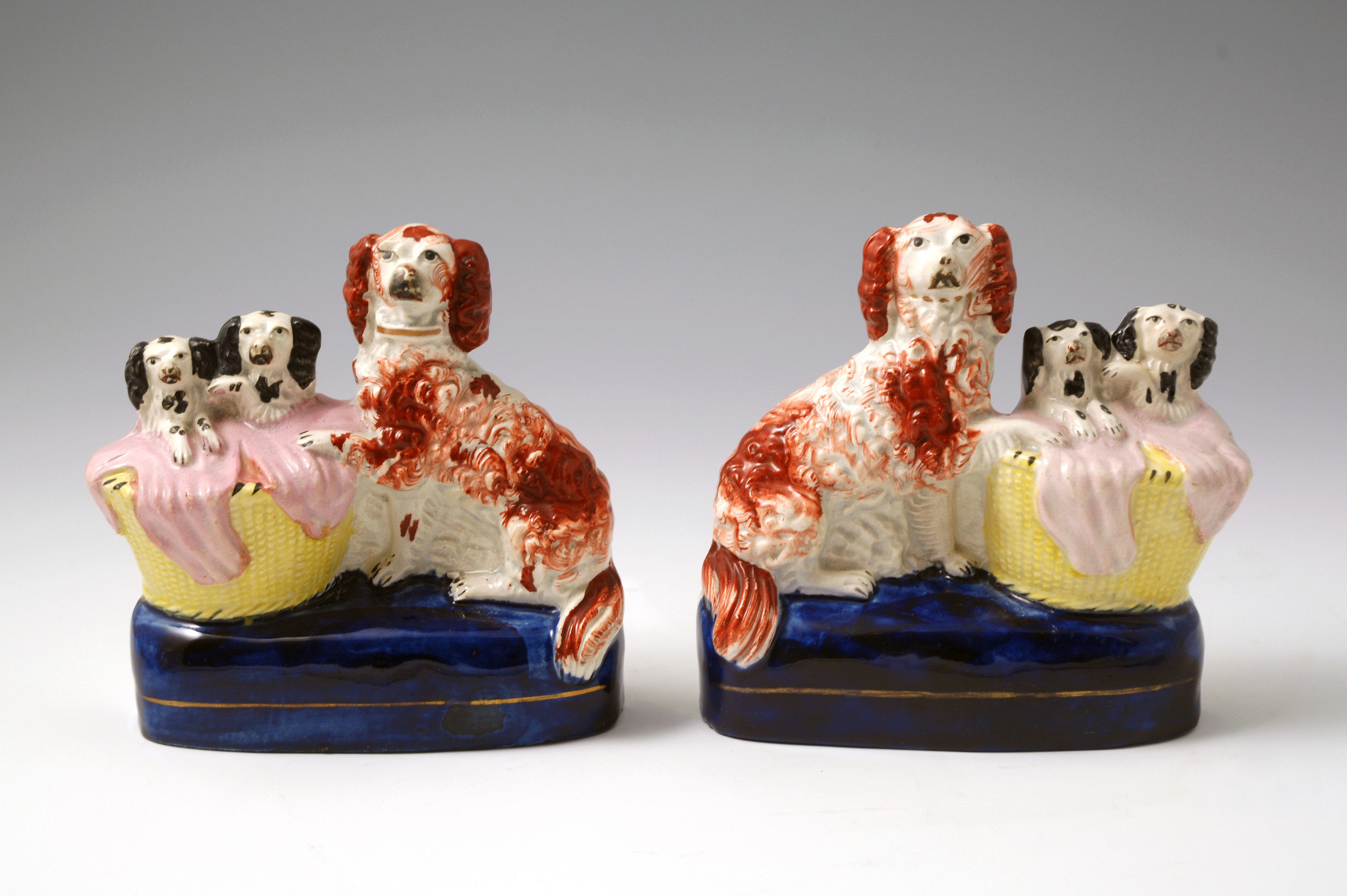 Pair Staffordshire pottery dogs with pups in  basket with blankets c1850