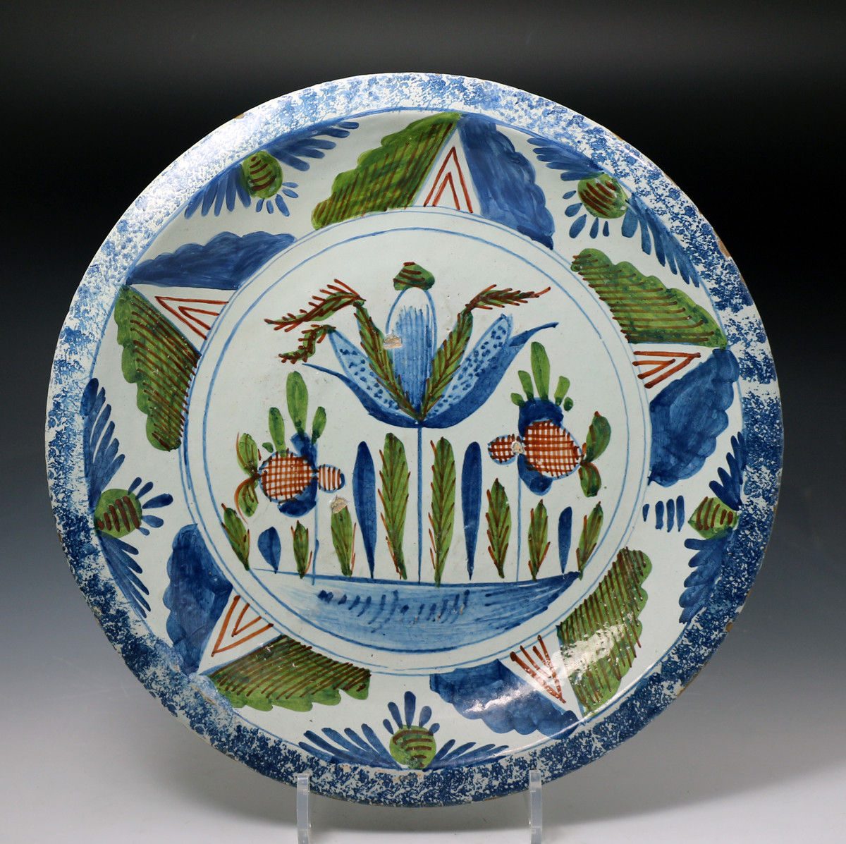 Antique English delftware charger 18th century decorated with a blue sponged border and tulip motif