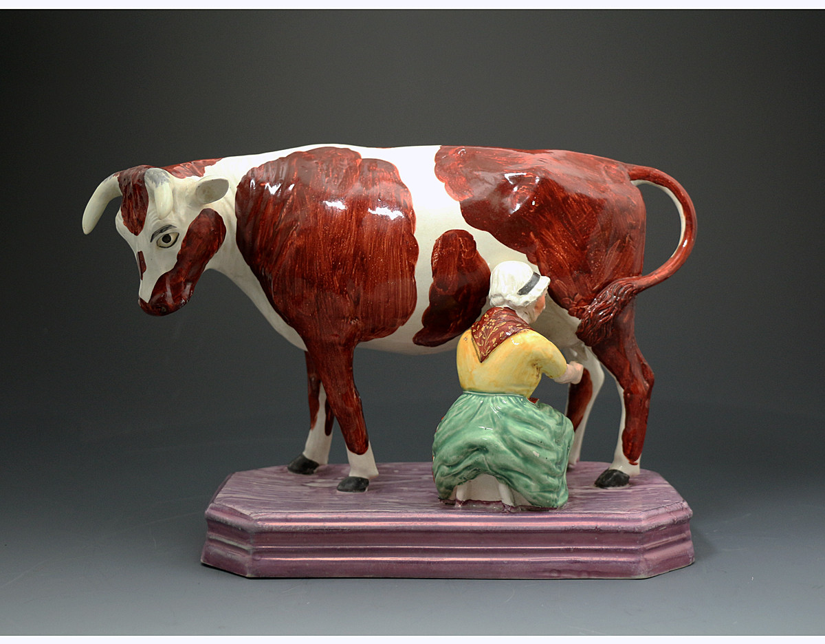 Antique English pottery figure of a cow and milk maid with a pink luster base Staffordshire pottery early 19th century