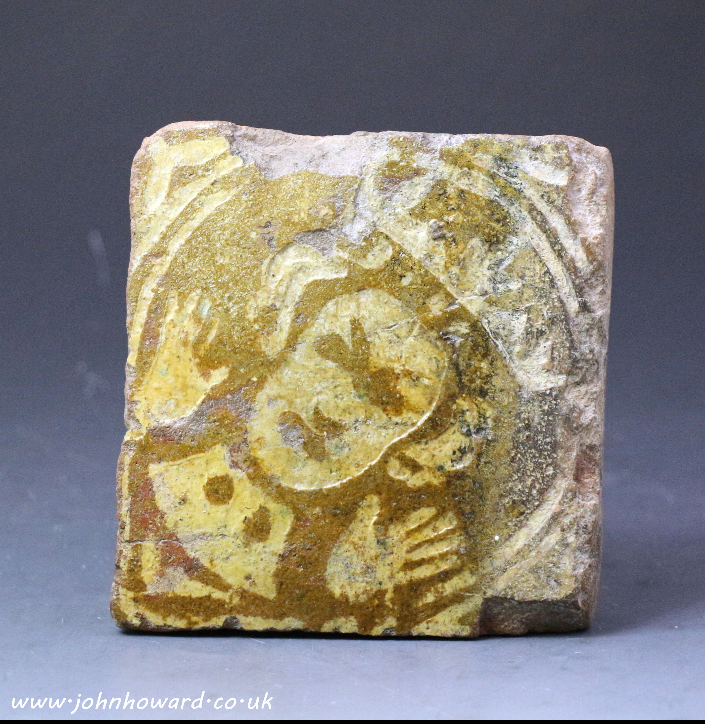 Antique medieval pottery tile with decorated in a pale yellow slip with  image of a Kings Head.13th century