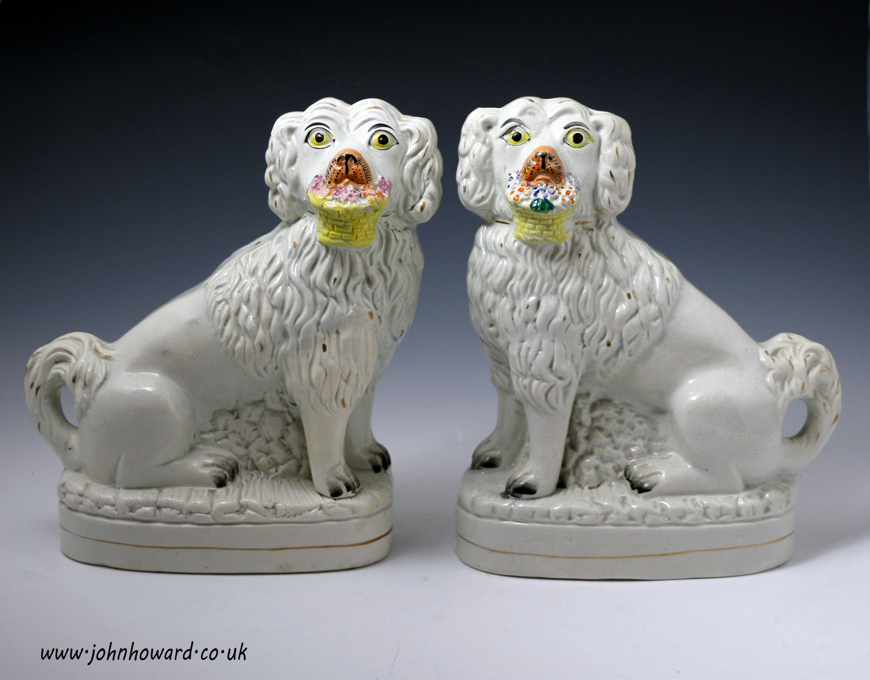 Staffordshire pottery dog figures with baskets of flowers mid 19th century
