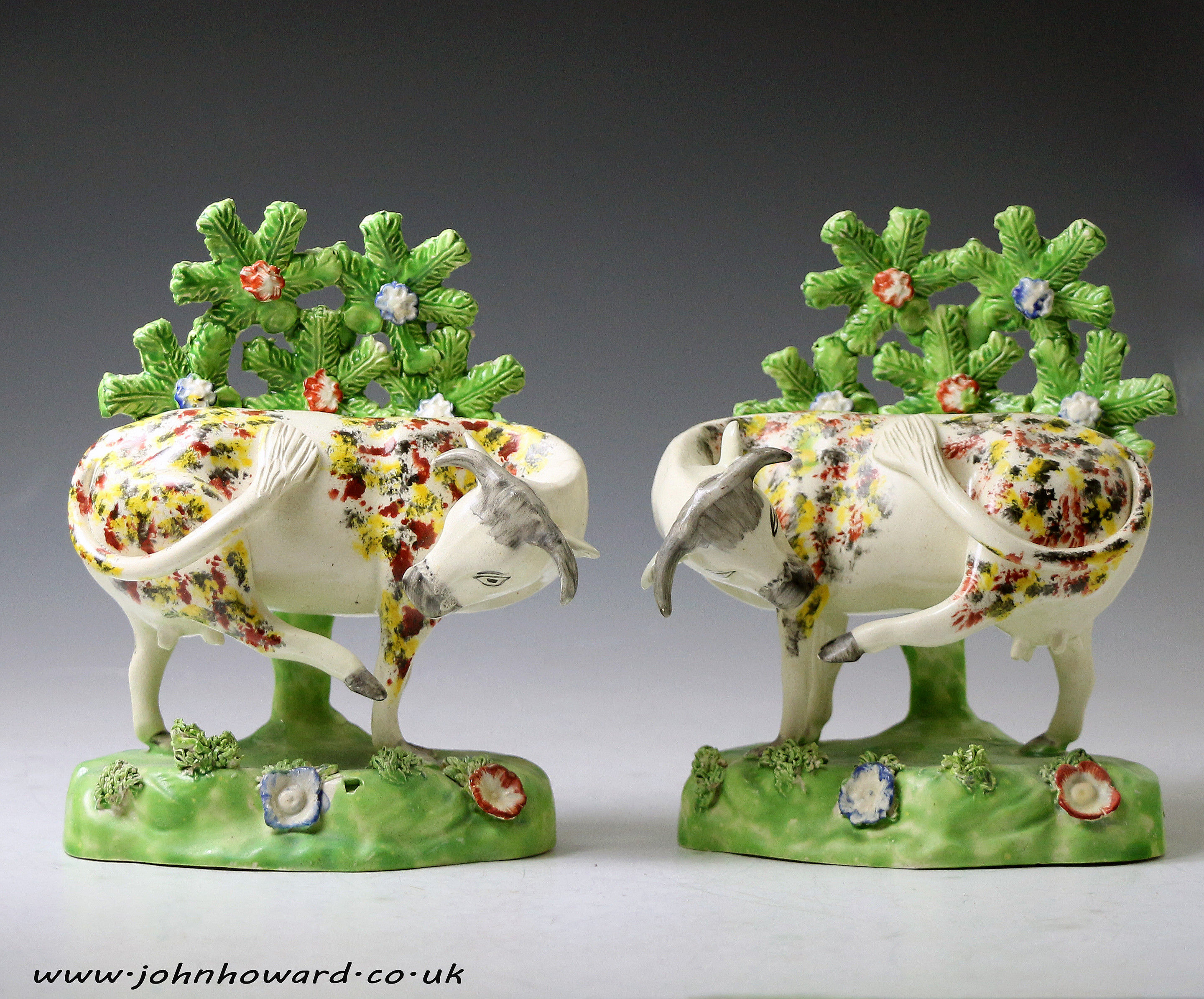 Pair of Staffordshire pottery figures of cows on bases with bocage pearlware English antique period early 19thc.