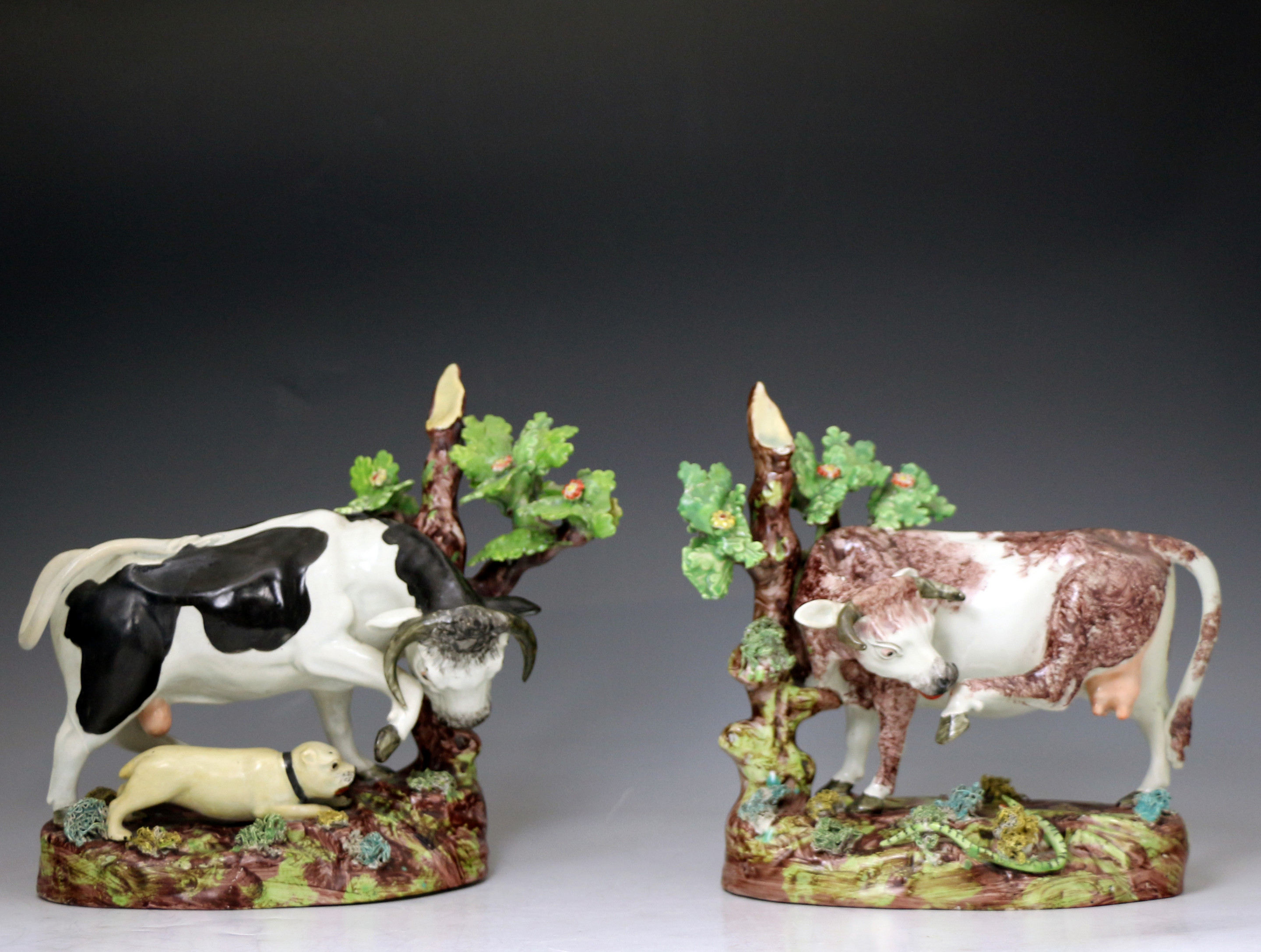 Pair of antique Staffordshire pottery figures of cow and bull  with tree and bocage early 19th century English.
