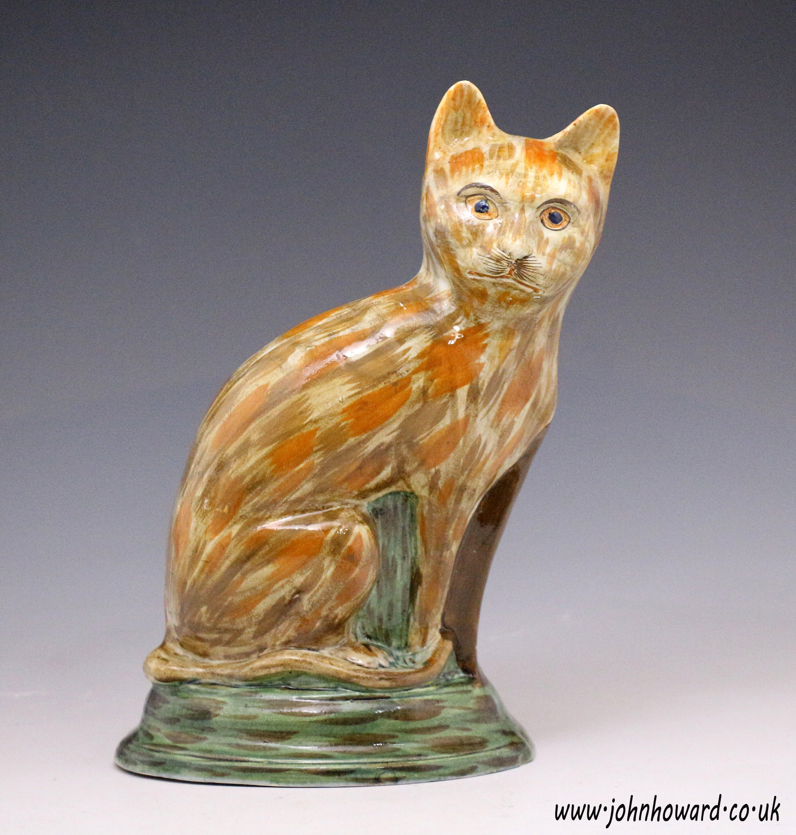 Antique Staffordshire prattware pottery figure of a seated cat.
